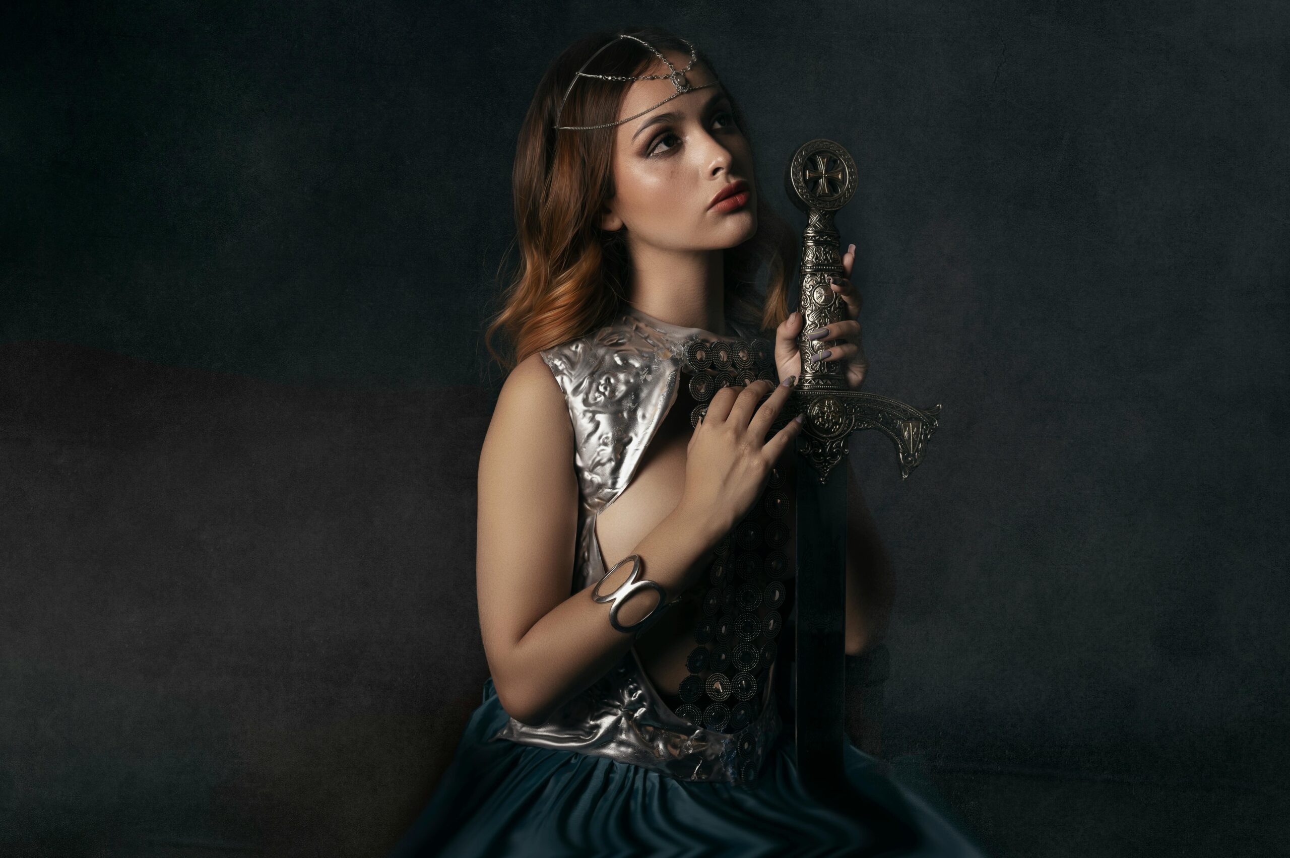 Portrait of a woman in medieval attire holding a decorative sword.